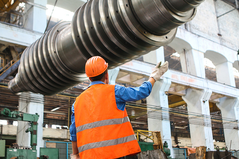 An employee conducting inspections on a large metal cylinder.